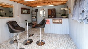 A bar area with two stools, a mirror, and a sign that reads 'Man Cave.' - Churn Dash Cottage (Derby)