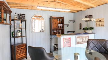 A bar area with wooden shelves, a glass table, and black leather chairs.