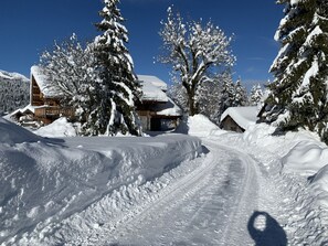 Eine verschneite Landschaft mit einer Holzhütte und einem mit Schnee bedeckten Baum.