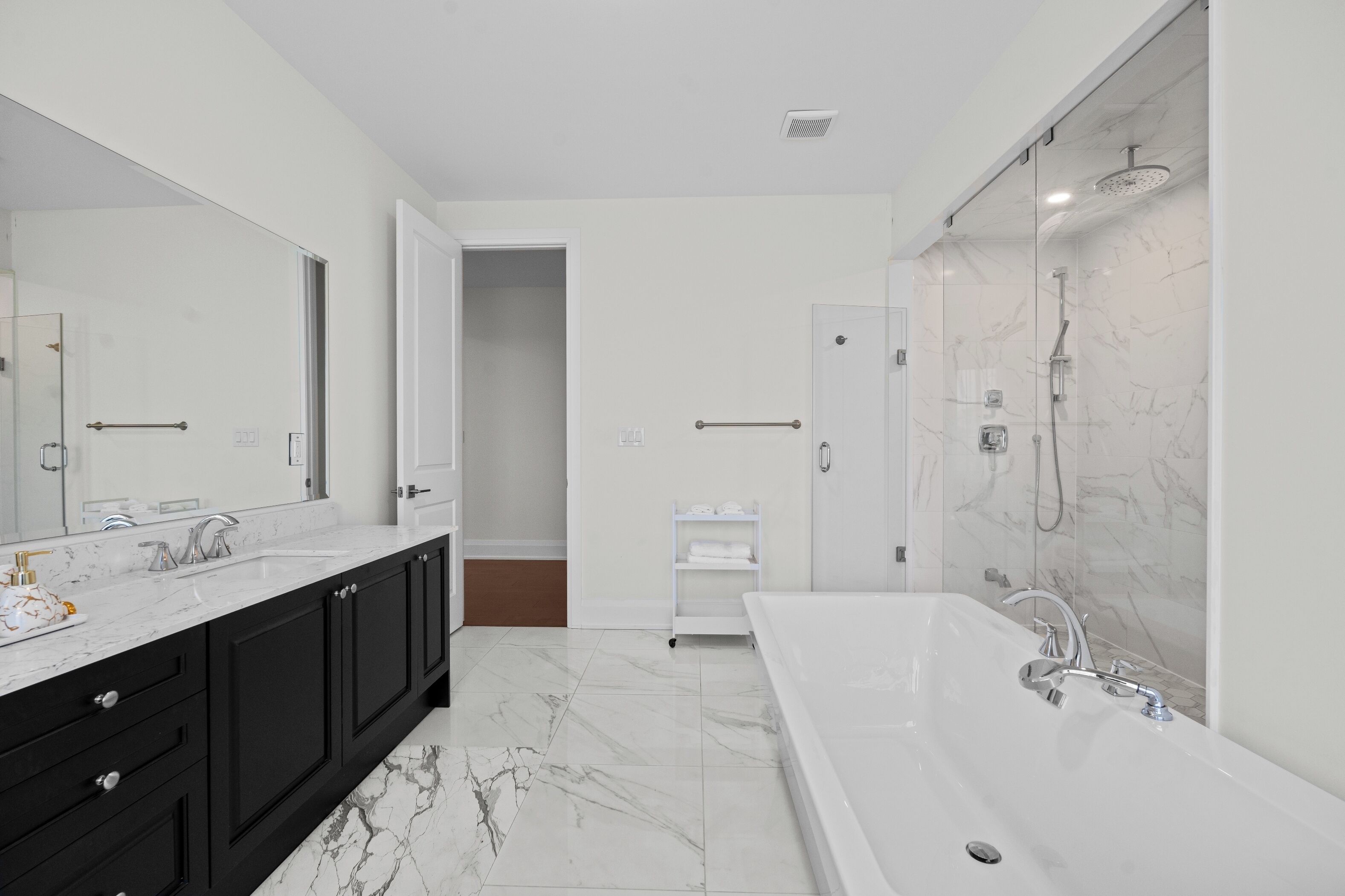 A modern bathroom with a large bathtub, a separate shower area, and a vanity with a mirror.