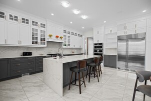 A modern kitchen with white cabinetry, a marble countertop, and stainless steel appliances.