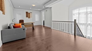 A spacious living area with a wooden floor, a grey sofa, a wooden coffee table, and a staircase with a railing. - GlobalStay 4 Bedrooms House in Brampton (Brampton)