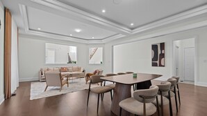 A spacious room with a large dining table surrounded by chairs, a sofa set, and a staircase leading to an upper level. - GlobalStay 4 Bedrooms House in Brampton (Brampton)