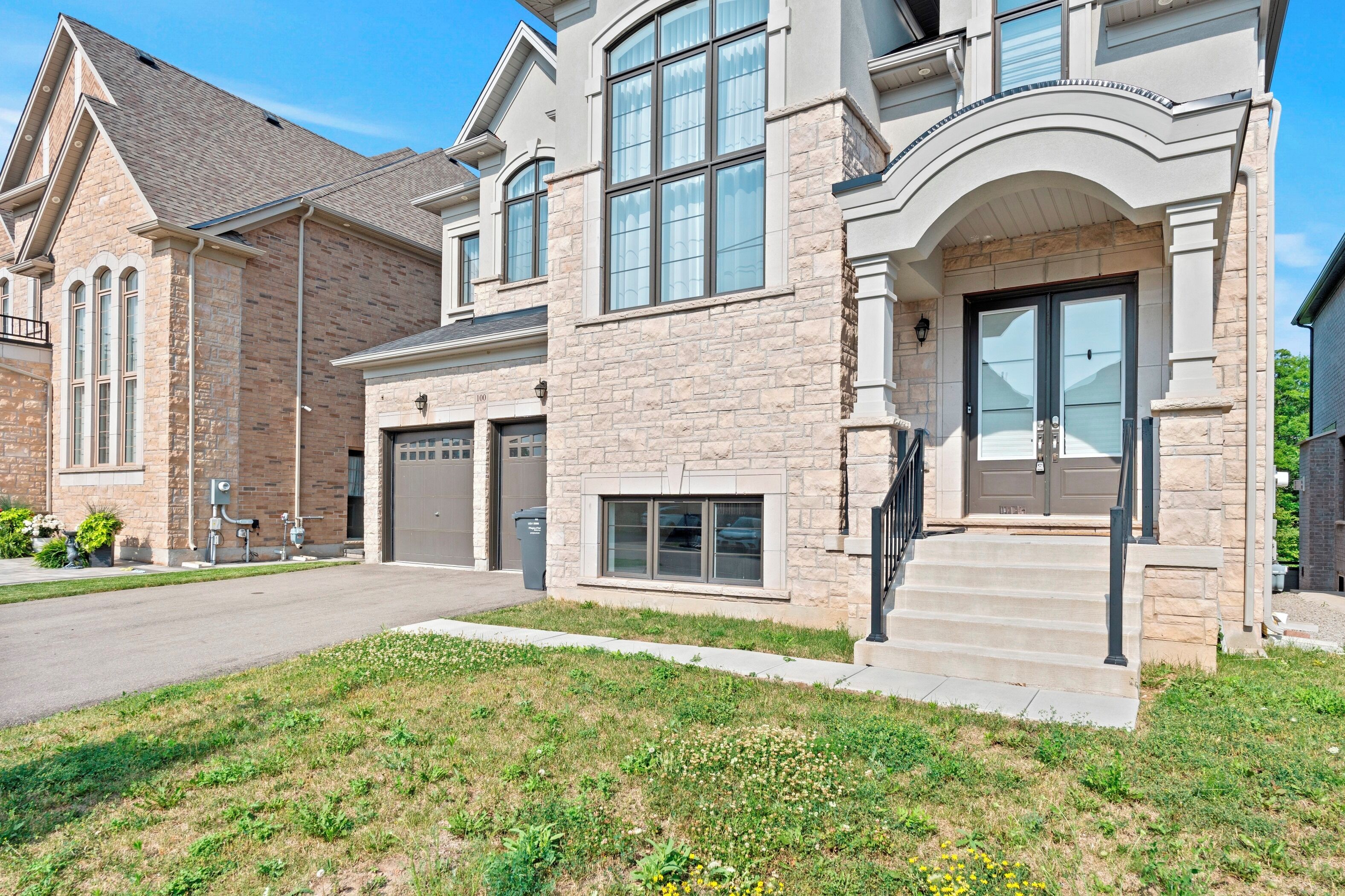 A two-story house with a stone facade, large windows, and a garage.