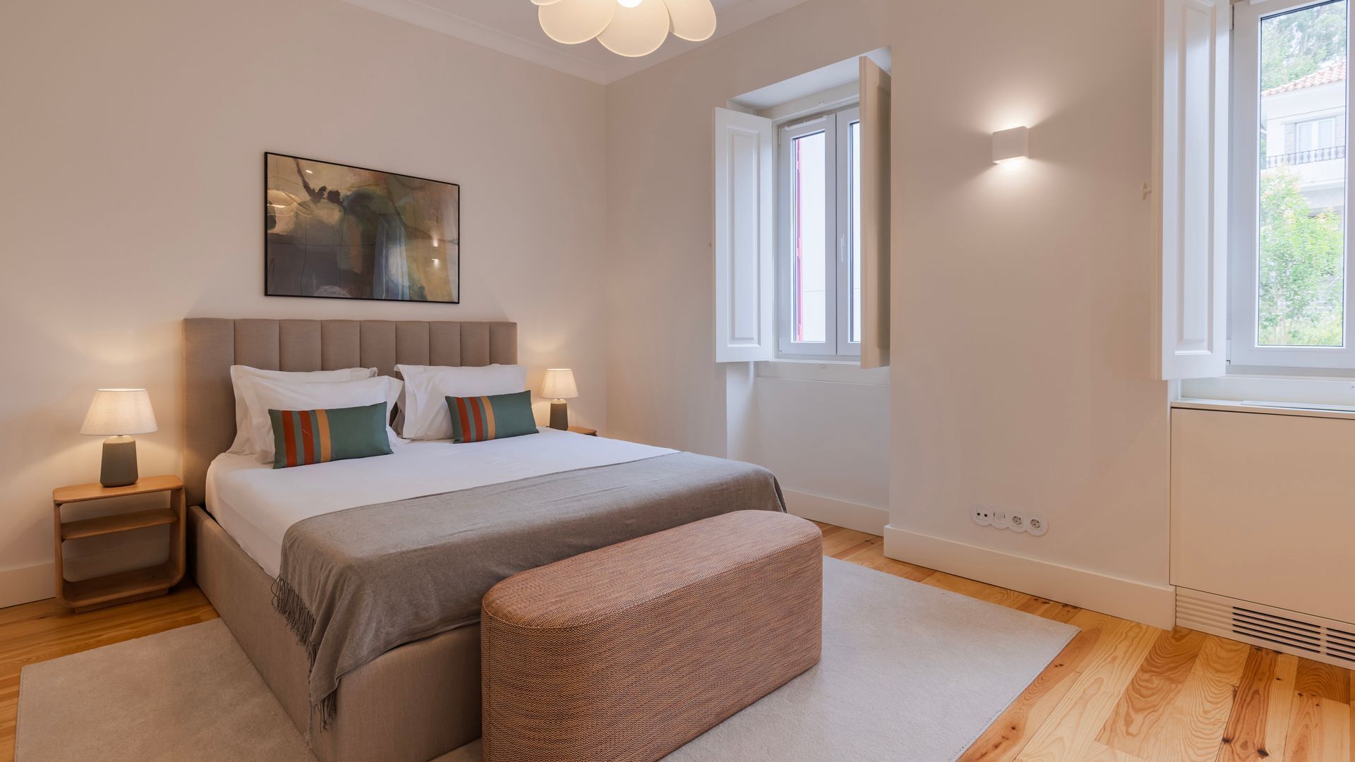 Ein modernes Schlafzimmer mit einem großen Bett, Nachttischlampen, einem Gemälde und einem Fenster.