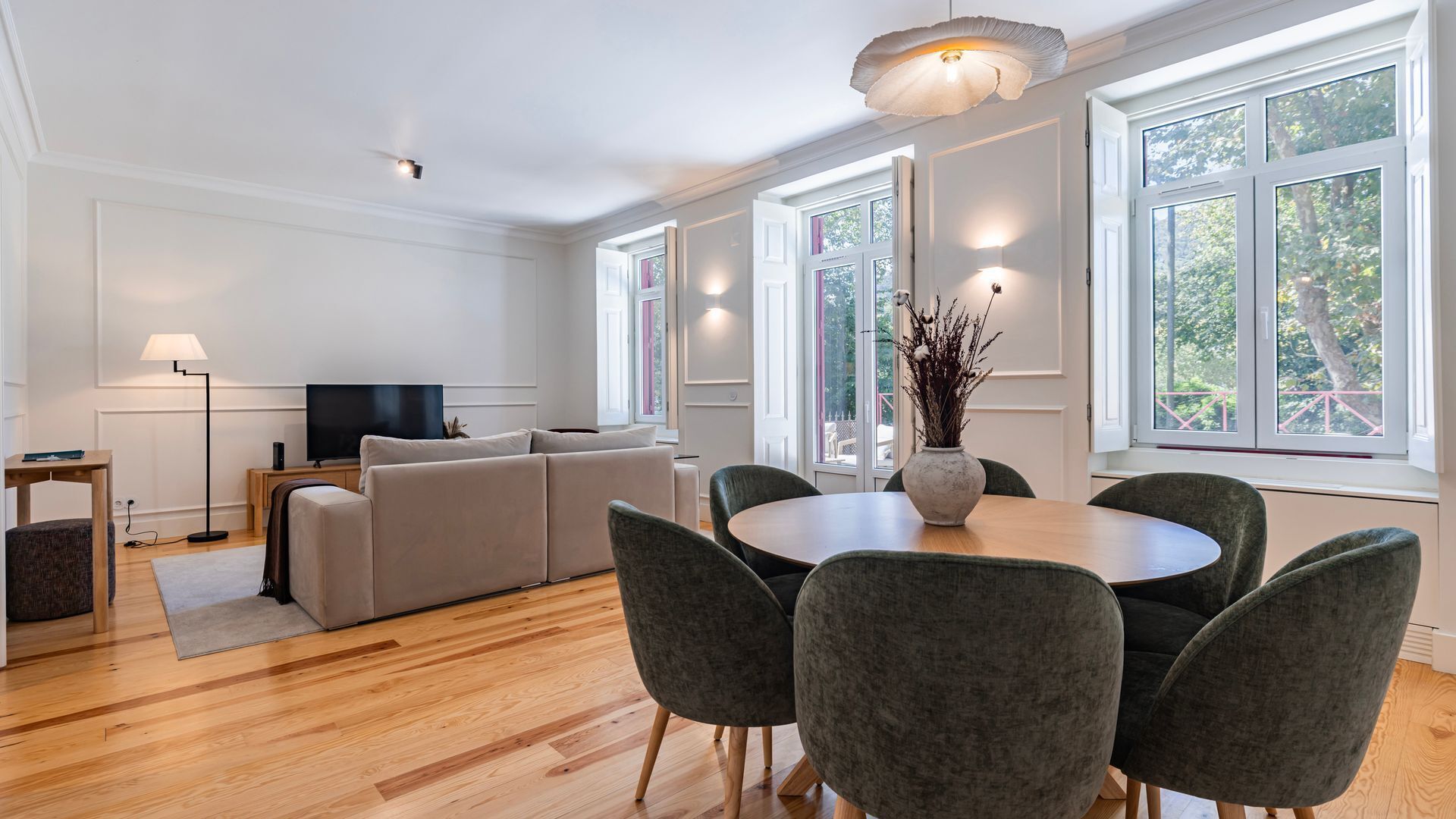 Un salon moderne avec un canapé, une table à manger et des chaises, un téléviseur et de grandes fenêtres.
