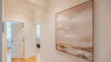 A hallway with a large abstract painting on the wall and a door leading to another room.