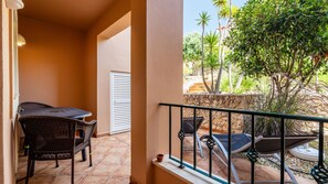A balcony with wicker furniture, a white door, and a view of a garden with palm trees. - Casa V2 Solarenga perto de Ferragudo by Lovelystay (Ferragudo)