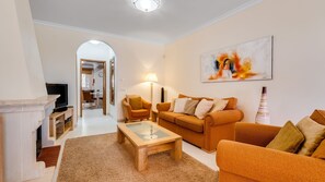 A living room with a sofa, a coffee table, and a lamp. There is a fireplace and a television. - Casa V2 Solarenga perto de Ferragudo by Lovelystay (Ferragudo)