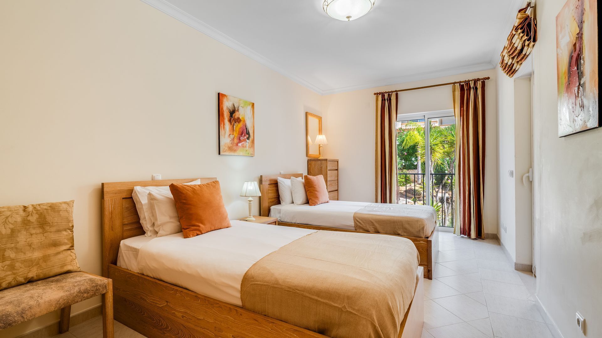 Une chambre d’hôtel avec deux lits, un coin salon et un balcon avec des rideaux.