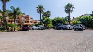 A parking lot with several cars, palm trees, and a building with balconies. - Casa V2 Solarenga perto de Ferragudo by Lovelystay (Ferragudo)