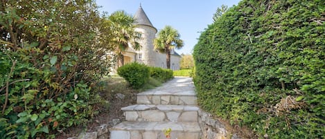 A stone staircase leading to a towered building with a conical roof, surrounded by lush greenery.