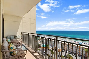 Ein Balkon mit Korbmöbeln und Blick auf Strand und Meer.