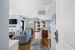 A modern living room with a sofa, a dining area, and a kitchen with a built-in oven. - *** Guests must be 21 years or older to book and check-in. *** (Panama City Beach)