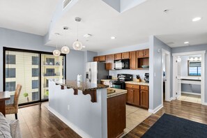 Een moderne keuken met een centraal eiland, houten kastjes en een groot raam.