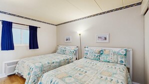 Ein Schlafzimmer mit zwei Betten, einem Fenster mit blauen Vorhängen und einer Heizung.