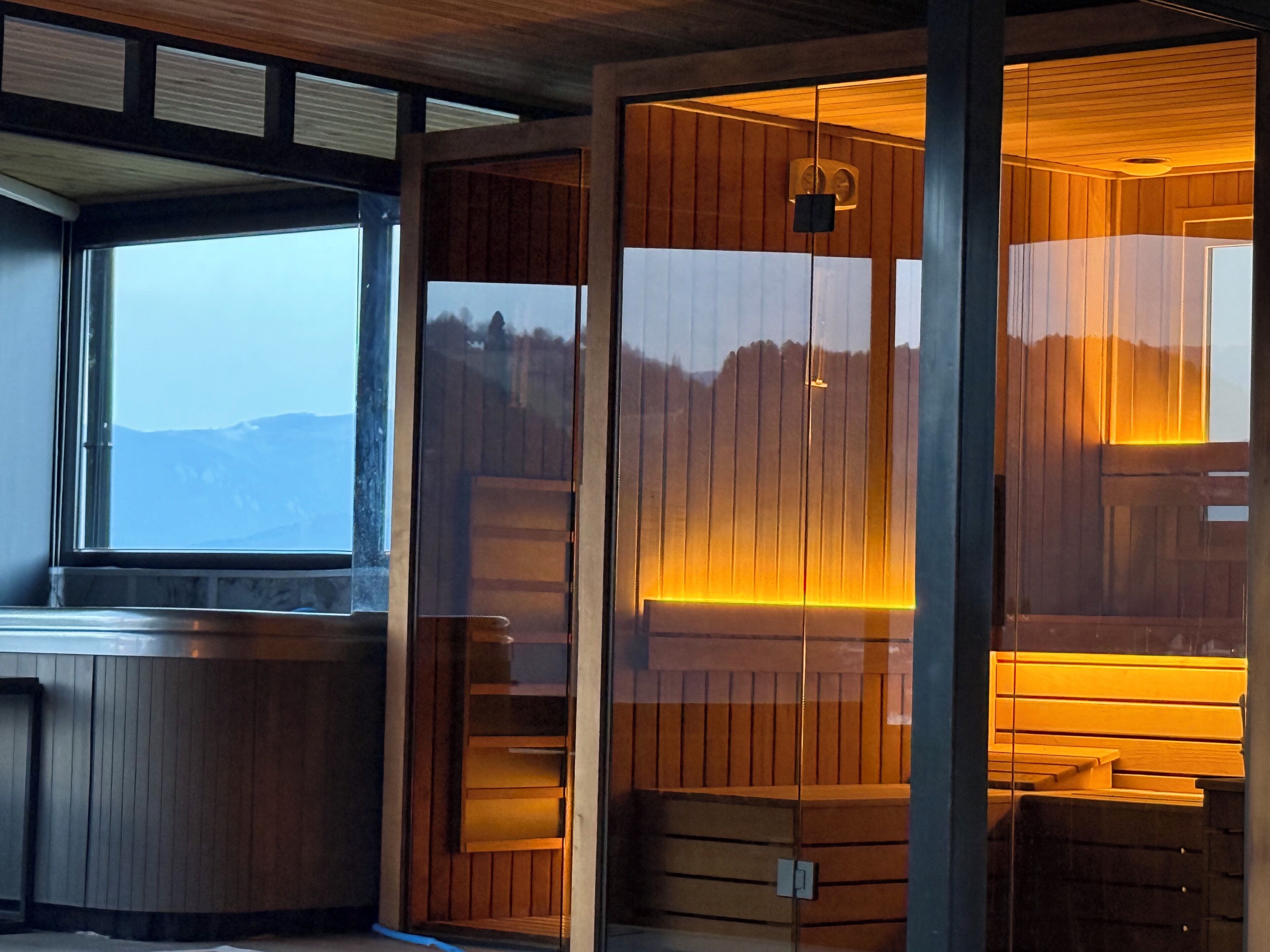 Ein Zimmer mit großem Fenster, Holzvertäfelung und Blick auf Berge.