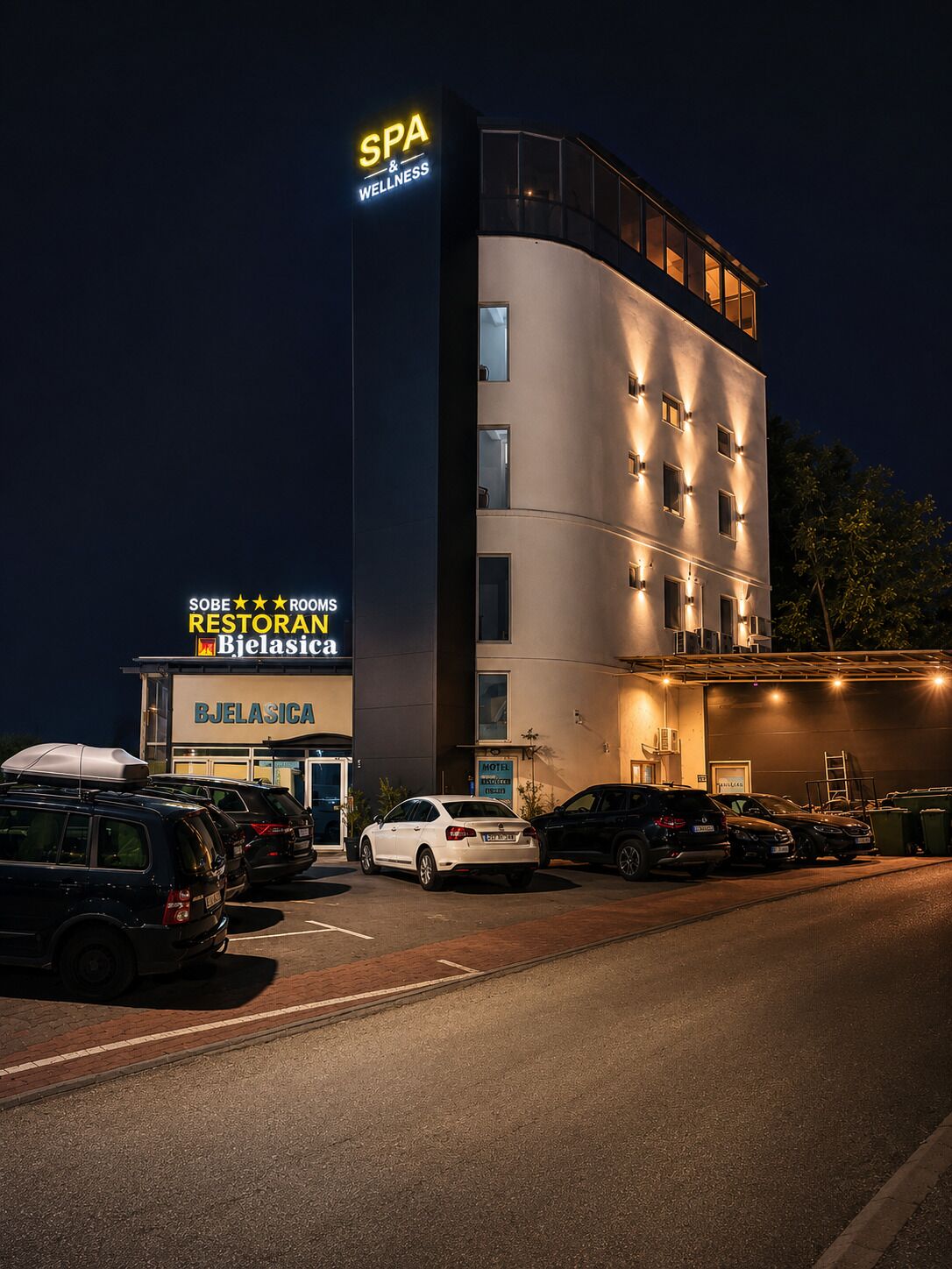 A multi-story hotel with a spa and wellness center, a restaurant, and a visible parking area with several cars.