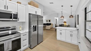 A modern kitchen with stainless steel appliances, white cabinetry, and a wooden floor. - Beautiful 2/2 Pool Home in Spring Hill (Spring Hill)