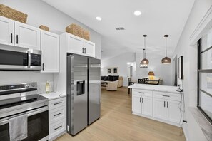 A modern kitchen with stainless steel appliances, white cabinetry, and a wooden floor. - Beautiful 2/2 Pool Home in Spring Hill (Spring Hill)