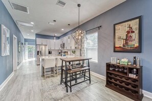 A modern kitchen with a central island, white cabinets, and a wine rack. - Modern West Tampa Bungalow - Live & Work In Style (Tampa)