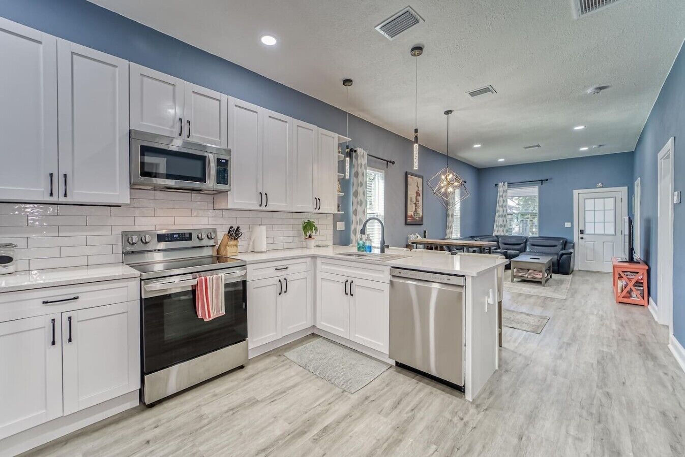 A modern kitchen with white cabinetry, stainless steel appliances, and a central island.
