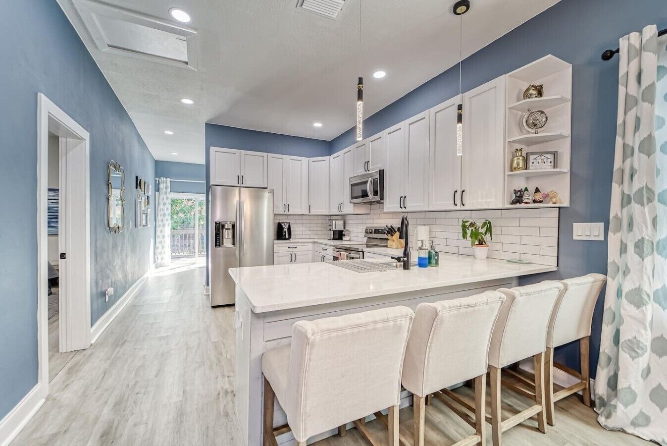 A modern kitchen with white cabinets, stainless steel appliances, and a central island with bar stools.