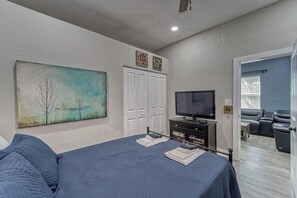 A bedroom with a bed, a television, a wardrobe, and a painting on the wall. - Modern West Tampa Bungalow - Live & Work In Style (Tampa)