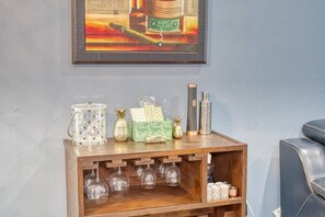 A wooden side table with a glass container, a pineapple-shaped candle, a green box with tissues, and two cylindrical objects. - Modern West Tampa Bungalow - Live & Work In Style (Tampa)