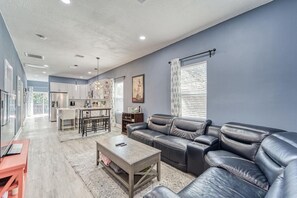 A modern living room with a leather sofa, a coffee table, and a kitchen in the background. - Modern West Tampa Bungalow - Live & Work In Style (Tampa)