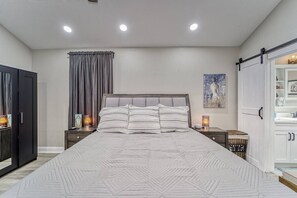 A bedroom with a large bed, bedside tables, a wardrobe, and a sliding door. - Modern West Tampa Bungalow - Live & Work In Style (Tampa)