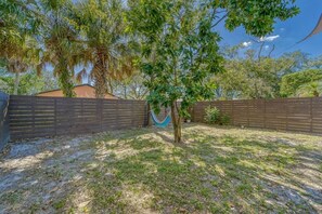 A fenced backyard with a hammock, trees, and a clear sky. - Modern West Tampa Bungalow - Live & Work In Style (Tampa)