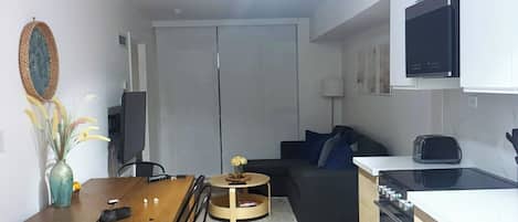 A compact living space with a dining area, kitchenette, and a sofa.
