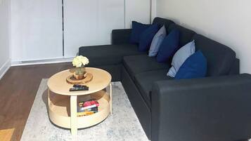 A modern living room with a dark grey sofa, a round wooden coffee table, and a floor lamp.