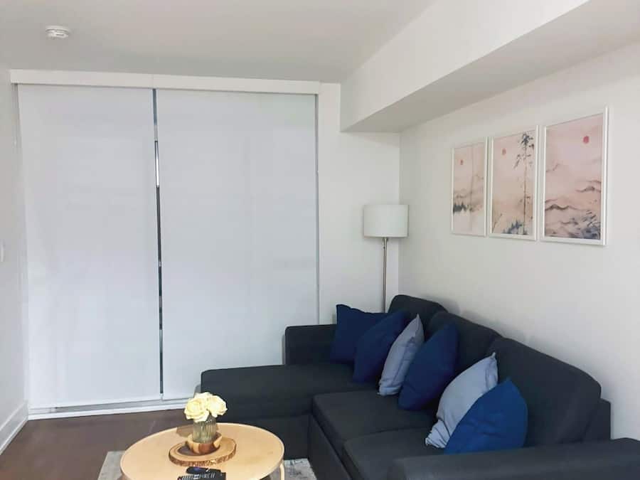 A modern living room with a dark grey sofa, a round wooden coffee table, and a floor lamp.