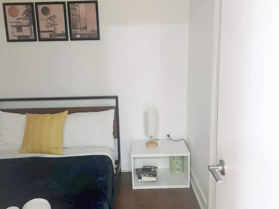 A hotel room with a bed, a nightstand, a lamp, and a door.