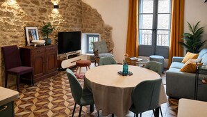 Un salon chaleureux avec un mur en pierre, un téléviseur, une table à manger et un canapé.