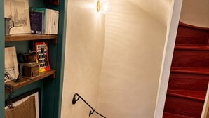 Un escalier avec une rampe rouge et un luminaire fixé au mur.