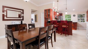 Een moderne keuken met een eethoek, met een houten tafel en stoelen, een keukeneiland met krukken en hanglampen.