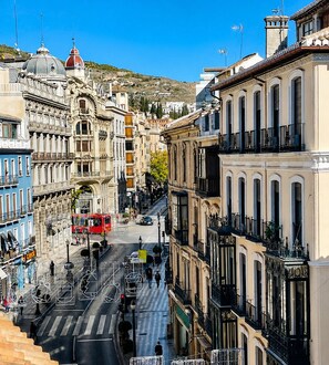 A street view with historic buildings, a red bus, and a pedestrian crossing. - La Perla Reyes Católicos Living: Standard Apartment (Granada)