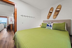 Una habitación con cama, piso de madera, vista al mar y perchero en la pared.