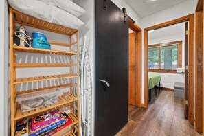 Una habitación con piso de madera, una puerta negra y vista a un comedor por una ventana.