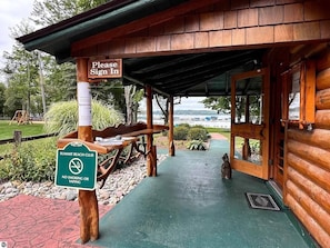 A wooden cabin with a 'Please Sign In' sign and a 'No Smoking or Vaping' sign. - Lake Bellaire View Condo | Pool • Beach Club (Bellaire)