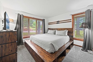 A bedroom with a wooden bed, a desk, and a TV.