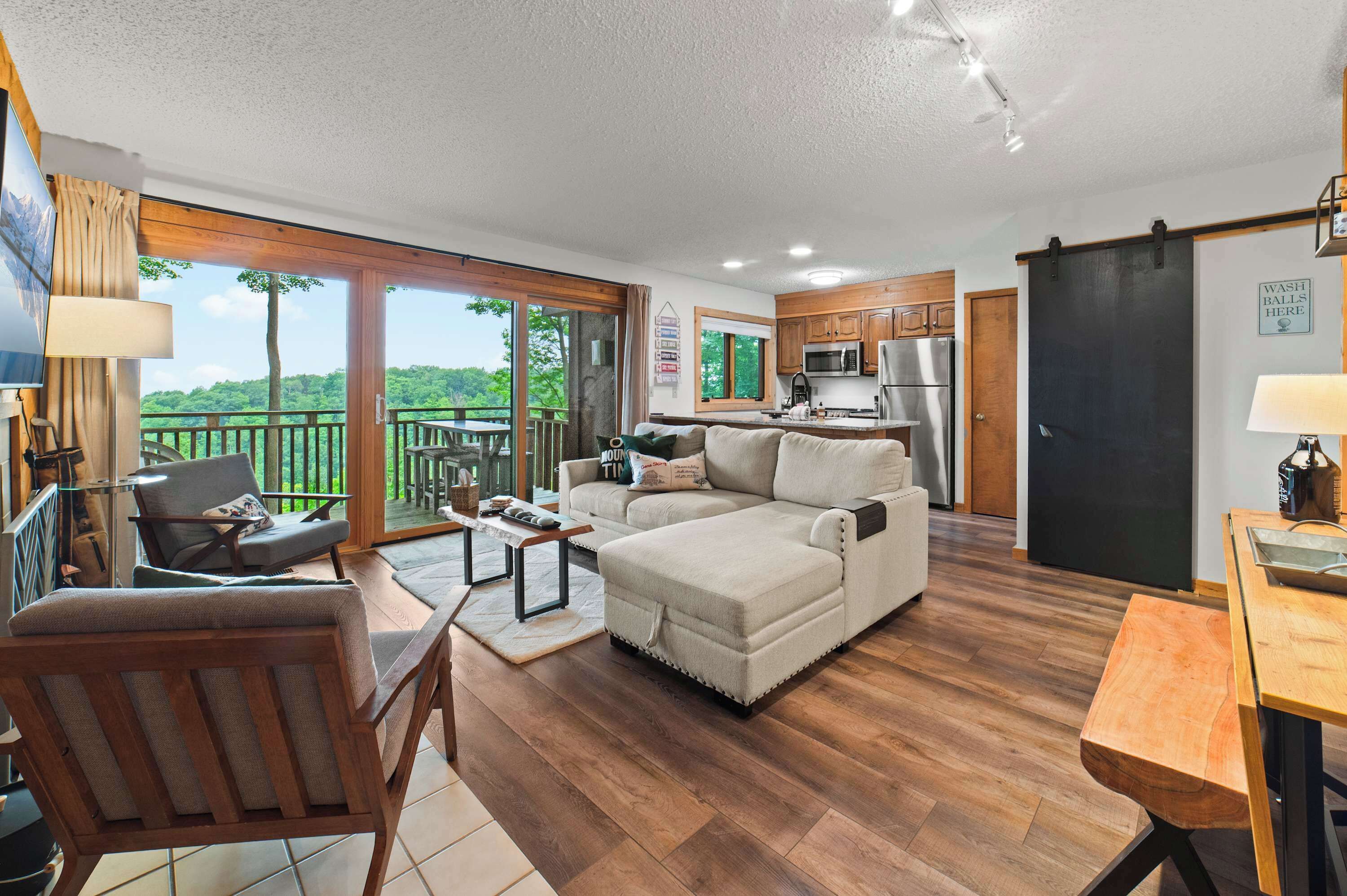 A spacious living area with a large sofa, a dining table, and a kitchen with wooden cabinets.