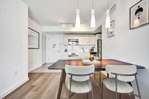 Eine moderne Küche mit weißen Schränken, einer dunklen Arbeitsplatte und einer Essecke mit zwei Stühlen und einem Tisch.