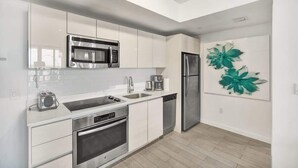 A modern kitchen with white cabinets, stainless steel appliances, and a backsplash. - Ocean and Canal View Condo Beach 8 min Pool 1906 (Hallandale Beach)