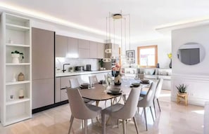 A modern kitchen with a dining area, featuring a central island, pendant lighting, and built-in shelving. - JUST 250 METRES FROM THE FAMOUS BOULEVARD DE LA CROISETTE AND ITS SANDY BEACHES (Cannes)