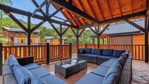 Eine Terrassenausstattung mit Holzpergola, einer Sofagarnitur und einem Couchtisch mit Glasplatte.