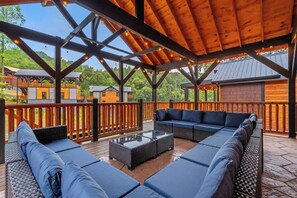 Eine Terrassenausstattung mit Holzpergola, einer Sofagarnitur und einem Couchtisch mit Glasplatte.